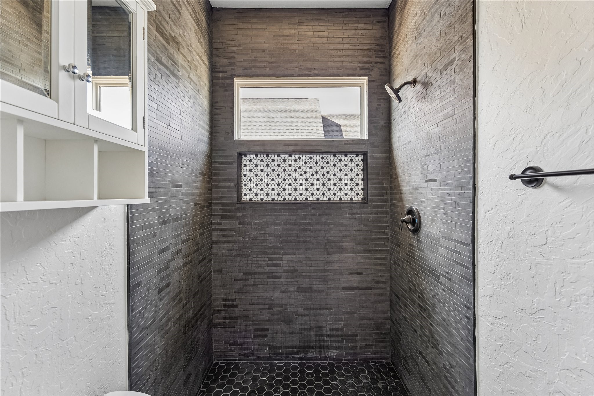 1408 West 23rd Street Houston, TX 77008 - Photo 35 of 40 Stylish walk-in shower with floor-to-ceiling tile, accent mosaic detail, and natural light from the overhead window.