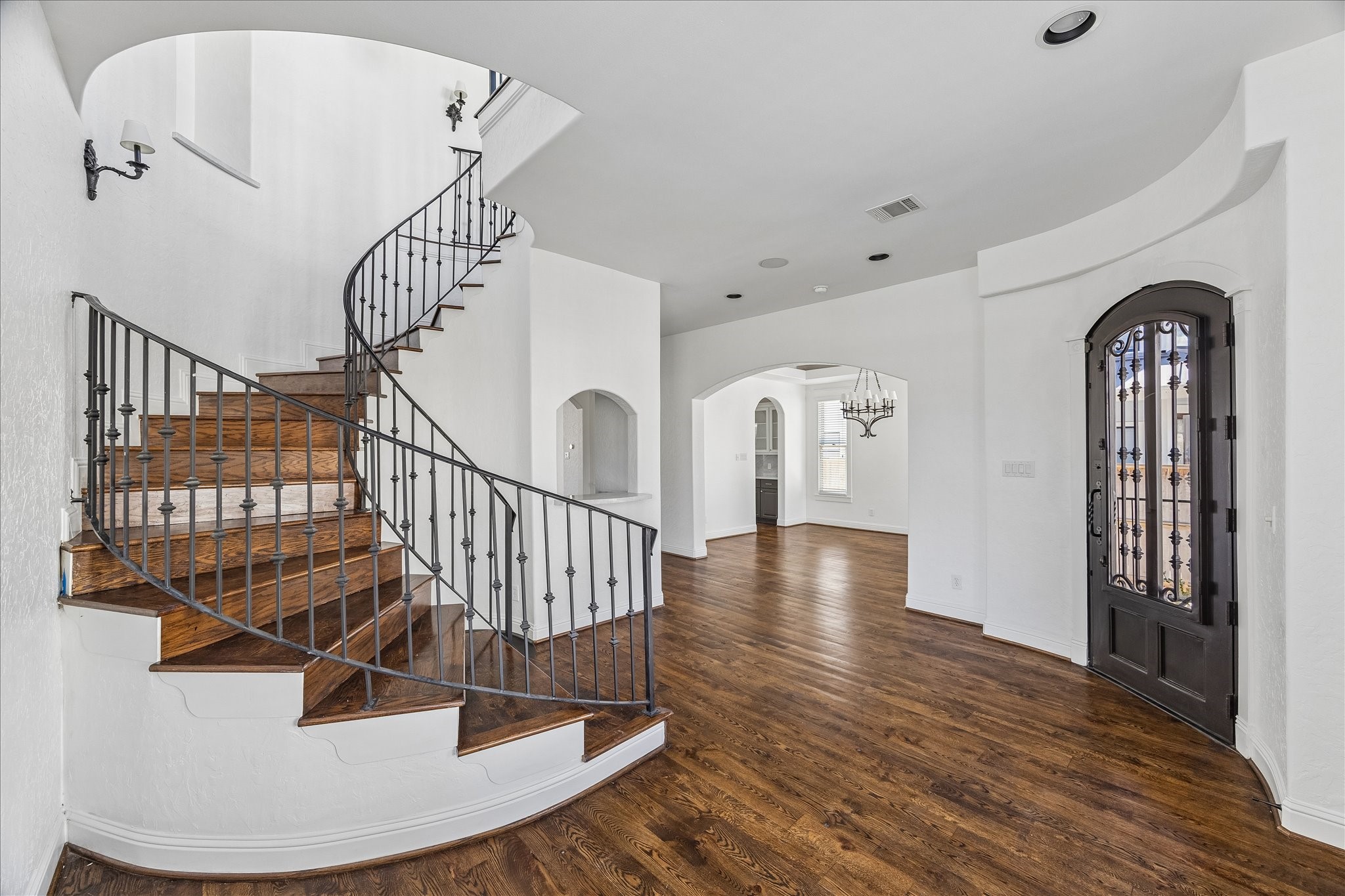 1408 West 23rd Street Houston, TX 77008 - Photo 10 of 40 Elegant foyer featuring a sweeping spiral staircase, rich hardwood floors, and arched openings that lead seamlessly into the home’s main living spaces.