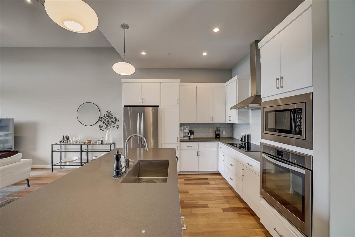 5921 Hiline Road, Unit 1204 Austin, TX 78734 - Photo 11 of 36 Kitchen with appliances with stainless steel finishes, pendant lighting, wall chimney exhaust hood, white cabinetry, and backsplash