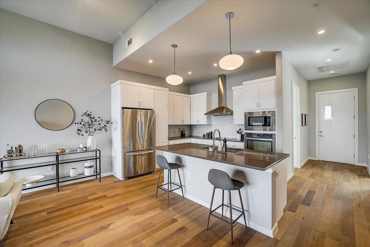 5921 Hiline Road, Unit 1204 Austin, TX 78734 - Photo 12 of 36 Kitchen with stainless steel appliances, white cabinets, wall chimney range hood, a kitchen island with sink, and a kitchen breakfast bar