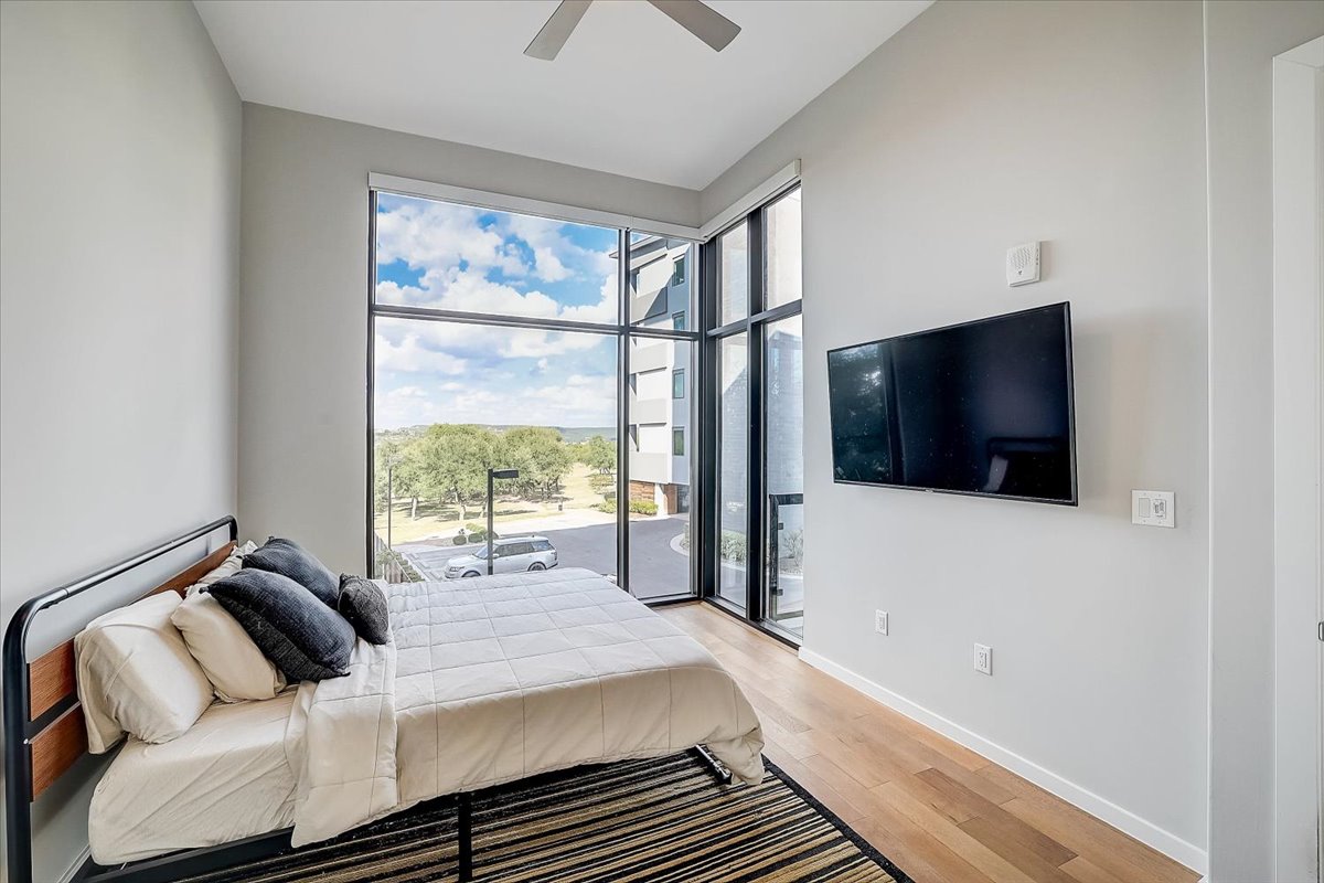 5921 Hiline Road, Unit 1204 Austin, TX 78734 - Photo 25 of 36 Bedroom with light wood finished floors, a ceiling fan, and access to exterior