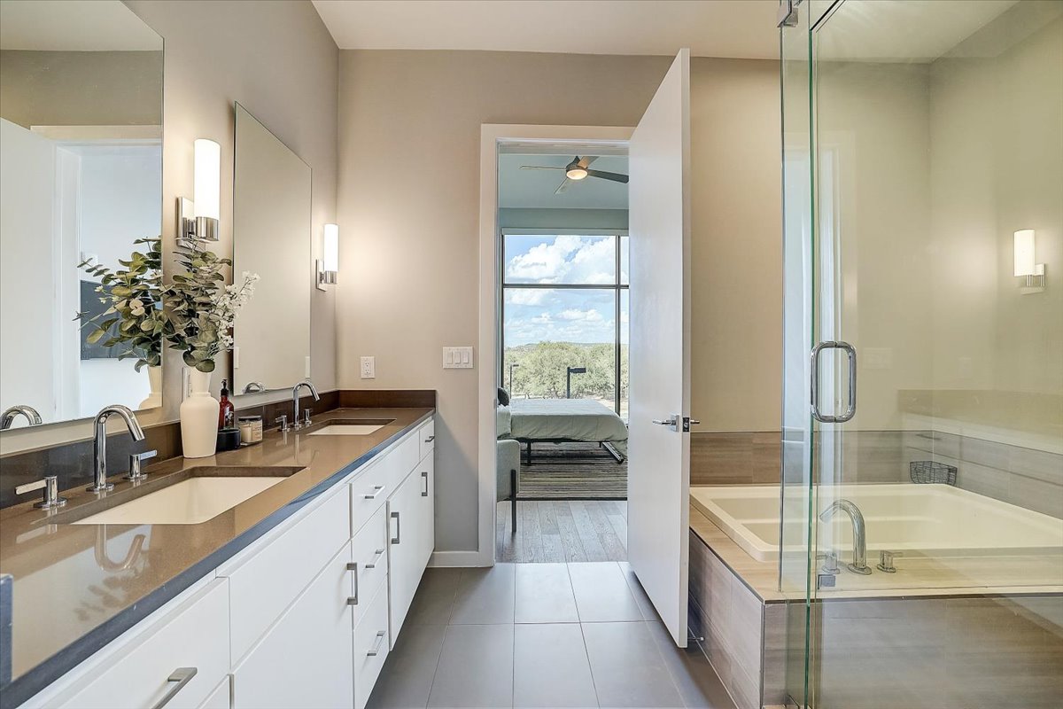 5921 Hiline Road, Unit 1204 Austin, TX 78734 - Photo 31 of 36 Ensuite bathroom featuring double vanity, a bath, dark tile patterned flooring, a ceiling fan, and a shower with door