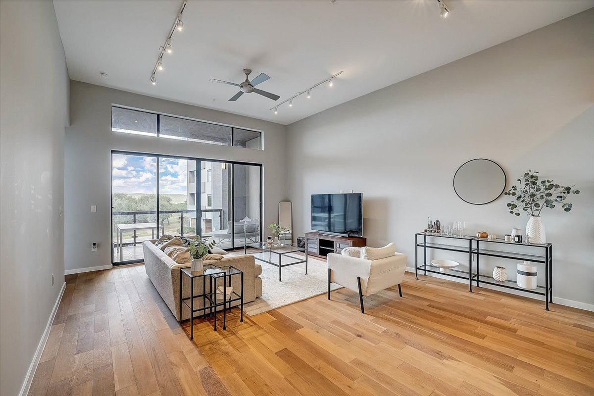 5921 Hiline Road, Unit 1204 Austin, TX 78734 - Photo 10 of 36 Living area with a ceiling fan, light wood-style flooring, rail lighting, and a high ceiling
