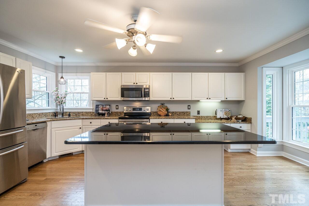 107 Needle Park Drive Cary, NC 27513 - Photo 12 of 29 a kitchen with stainless steel appliances granite countertop a refrigerator a stove top oven a sink dishwasher and white cabinets with wooden floor