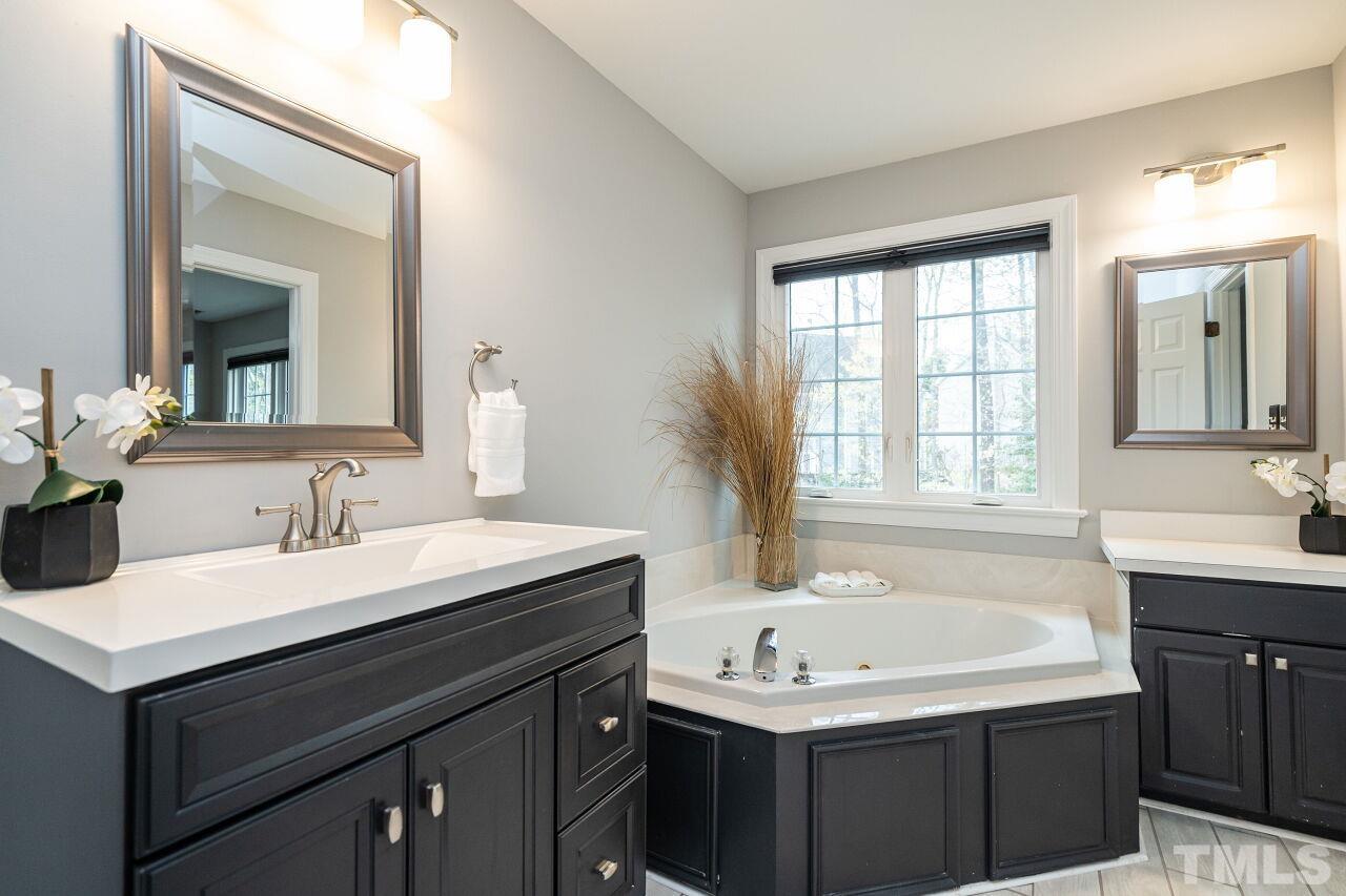 107 Needle Park Drive Cary, NC 27513 - Photo 16 of 29 a bathroom with a sink vanity tub and a mirror