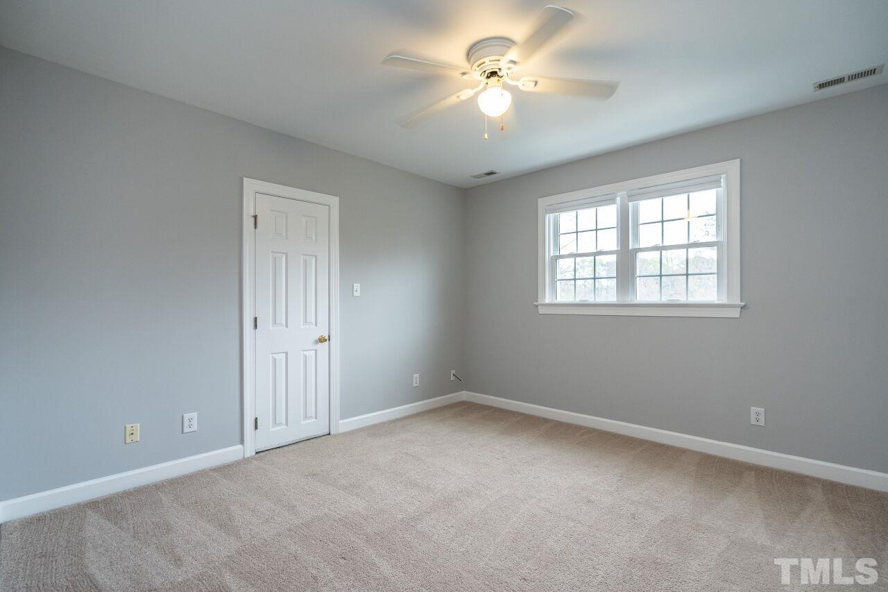 107 Needle Park Drive Cary, NC 27513 - Photo 19 of 29 an empty room with chandelier fan and windows