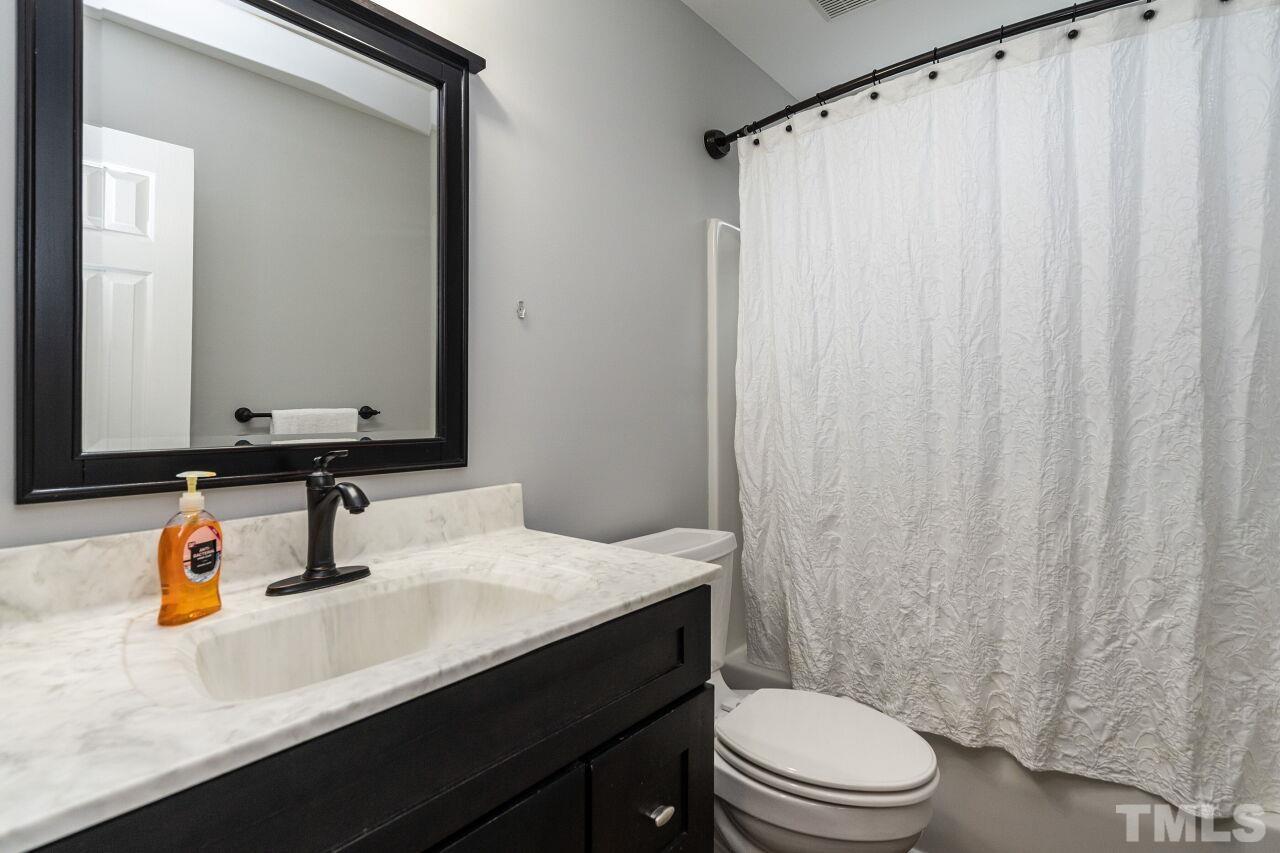 107 Needle Park Drive Cary, NC 27513 - Photo 20 of 29 a bathroom with a sink a toilet a mirror and shower curtain