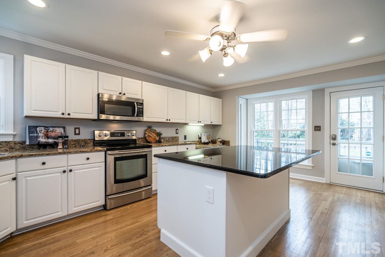 107 Needle Park Drive Cary, NC 27513 - Photo 9 of 29 a kitchen with stainless steel appliances kitchen island granite countertop a stove a sink and white cabinets