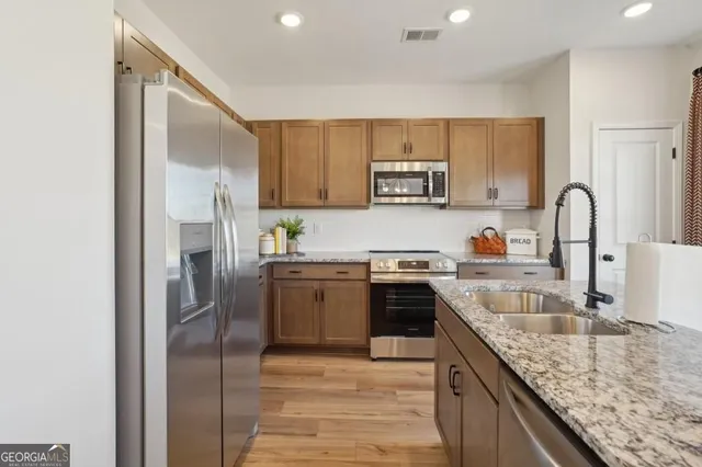 a kitchen with granite countertop a refrigerator stove top oven and sink