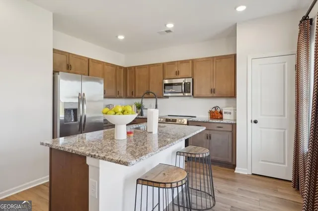 a kitchen with kitchen island granite countertop wooden floor white cabinets and stainless steel appliances