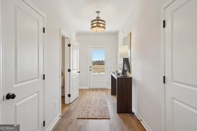 a view of a hallway view with wooden floor and a bathroom