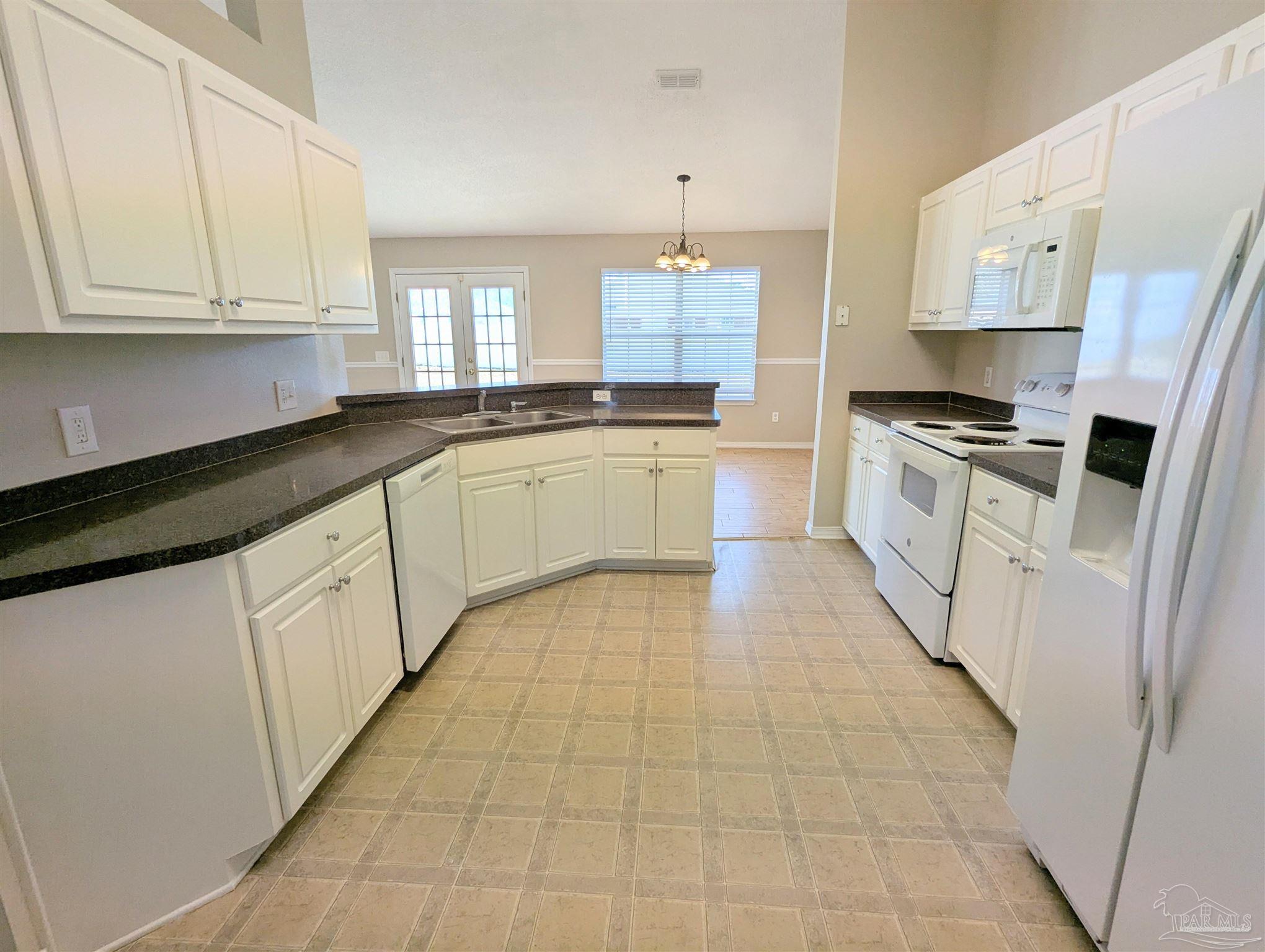 7108 Fitzpatrick Road Pensacola, FL 32526 - Photo 12 of 30 a large kitchen with stainless steel appliances granite countertop a stove a sink and white cabinets
