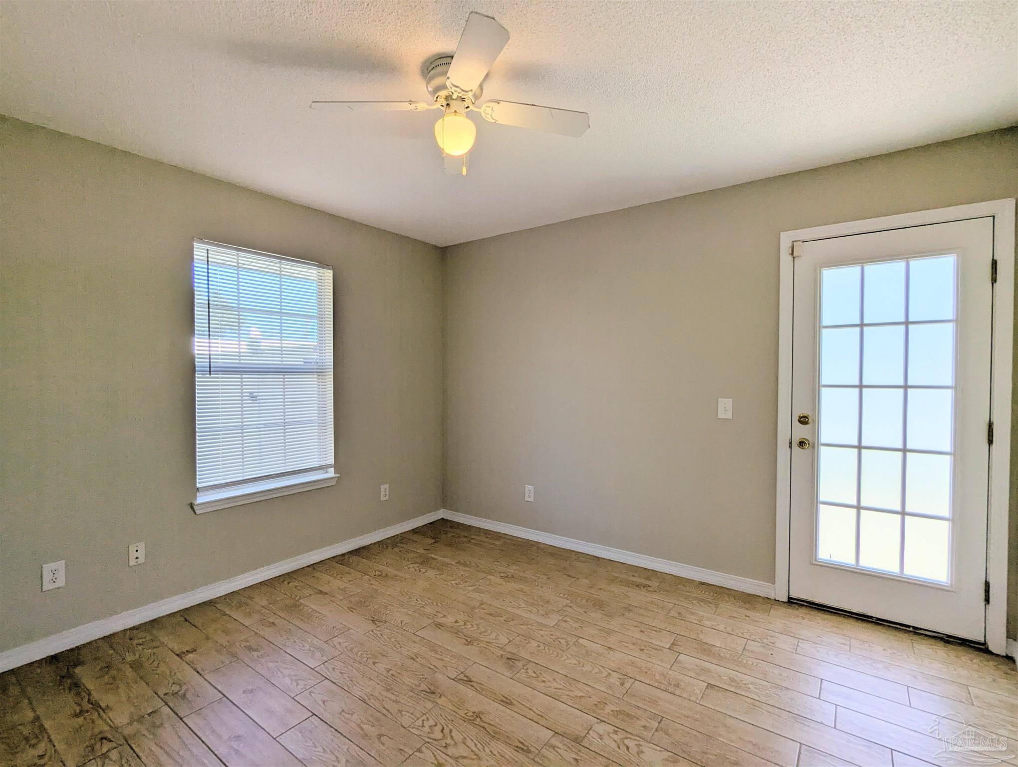 7108 Fitzpatrick Road Pensacola, FL 32526 - Photo 23 of 30 an empty room with wooden floor chandelier fan and windows