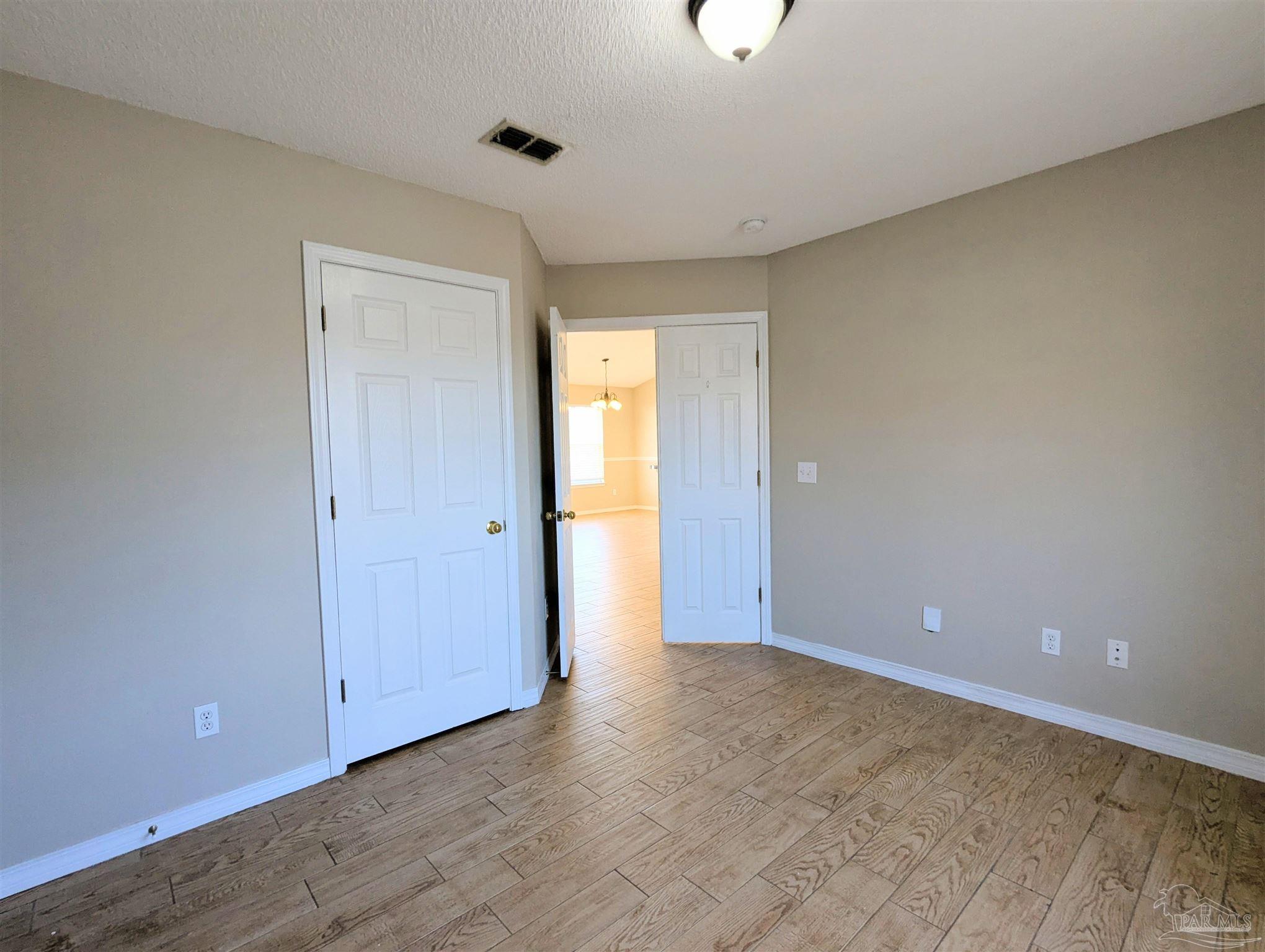 7108 Fitzpatrick Road Pensacola, FL 32526 - Photo 4 of 30 a view of an empty room with wooden floor and a window