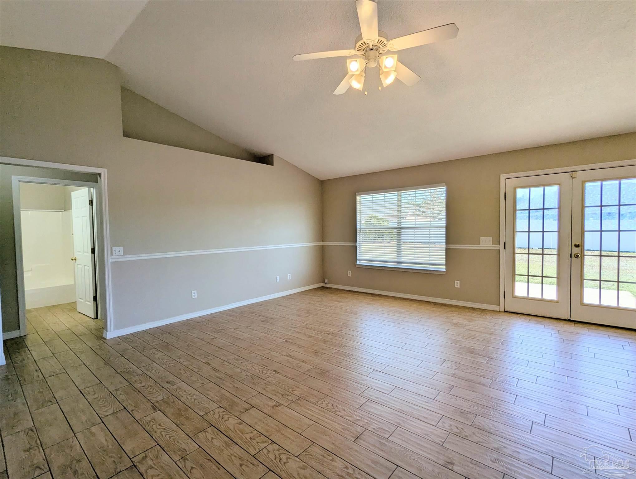 7108 Fitzpatrick Road Pensacola, FL 32526 - Photo 5 of 30 an empty room with wooden floor chandelier fan and windows