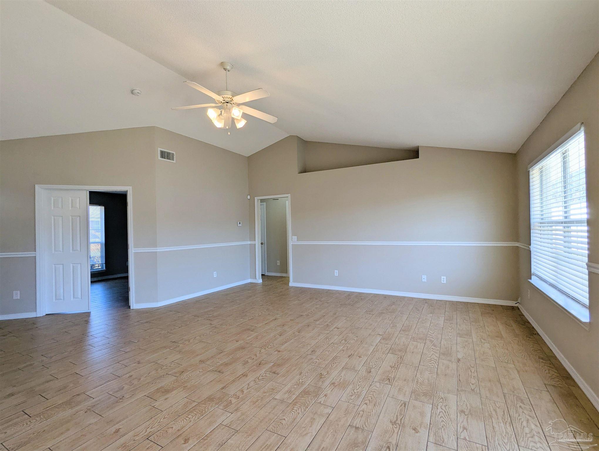 7108 Fitzpatrick Road Pensacola, FL 32526 - Photo 6 of 30 an empty room with wooden floor fan and windows