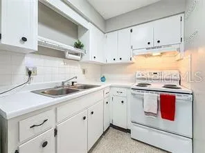 a kitchen with granite countertop white cabinets and white appliances