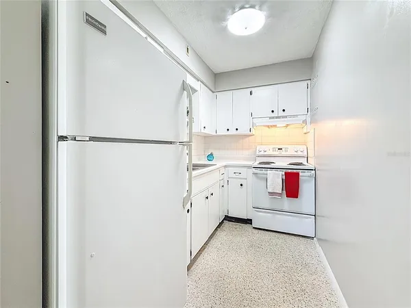 a view of a kitchen with refrigerator and white cabinets