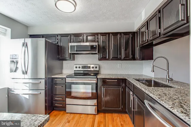 a kitchen with stainless steel appliances granite countertop a refrigerator stove and sink