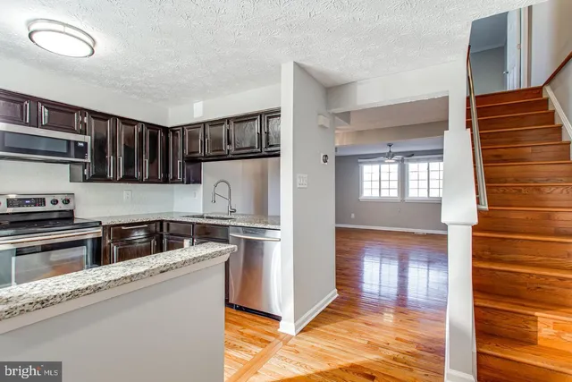 a kitchen with stainless steel appliances granite countertop a refrigerator a stove and a sink with wooden cabinets