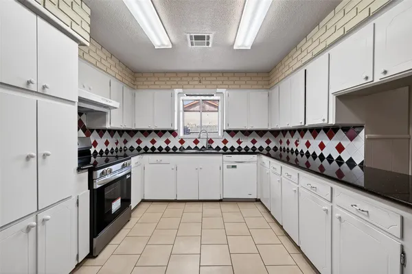 a kitchen with granite countertop white cabinets and stainless steel appliances