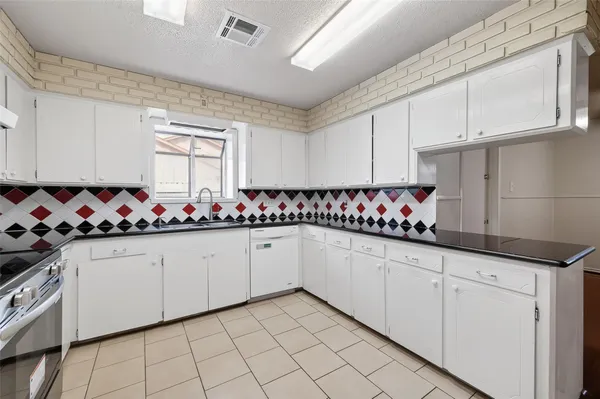 a kitchen with granite countertop white cabinets and sink