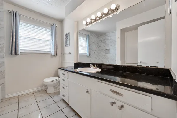 a bathroom with a granite countertop sink a toilet and a mirror