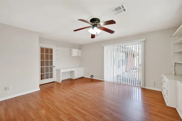 a view of empty room with wooden floor and fan
