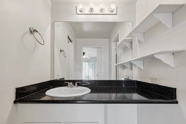 a bathroom with a granite countertop sink a mirror and a shower