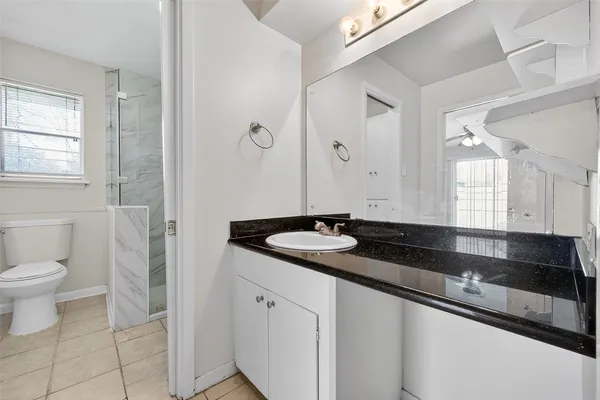 a bathroom with a granite countertop sink and a toilet