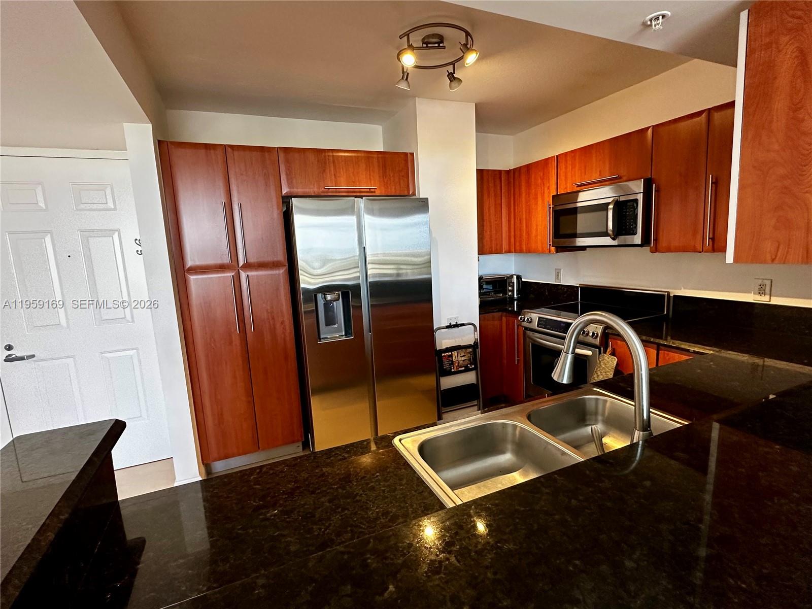 3232 Southwest 22nd Terrace, Unit 1604 Miami, FL 33145 - Photo 13 of 40 a kitchen with stainless steel appliances granite countertop a refrigerator a stove and a sink with wooden floor