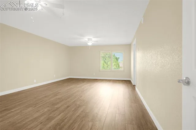 an empty room with wooden floor and windows
