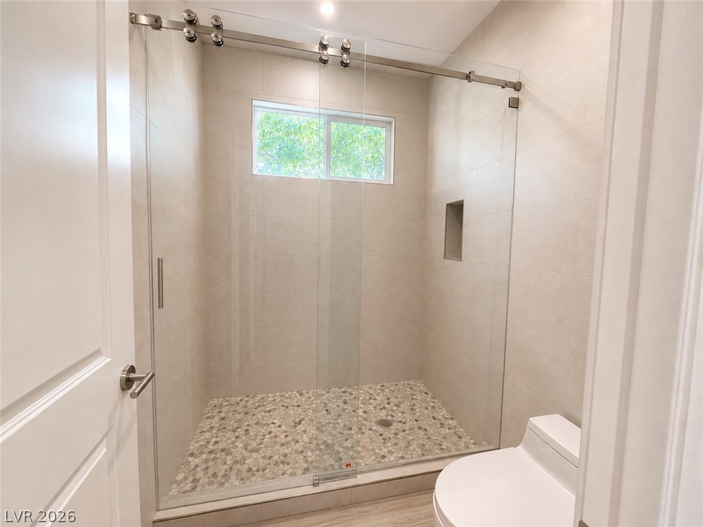 5446 Pine Ranch Street Las Vegas, NV 89113 - Photo 4 of 7 Stone tile floors and a glass-enclosed shower highlight this modern bathroom space.