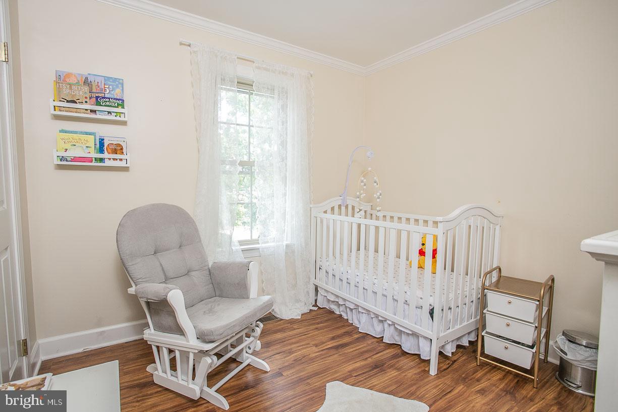 295 Sugartown Road Wayne, PA 19087 - Photo 23 of 36 a living room with furniture a baby crib and a wooden floor