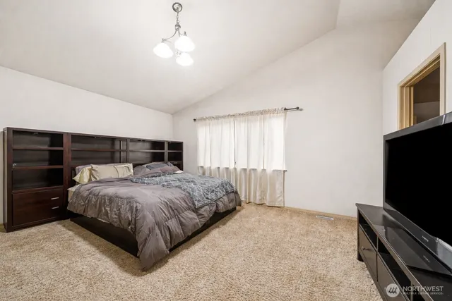 a spacious bedroom with a bed and a flat screen tv