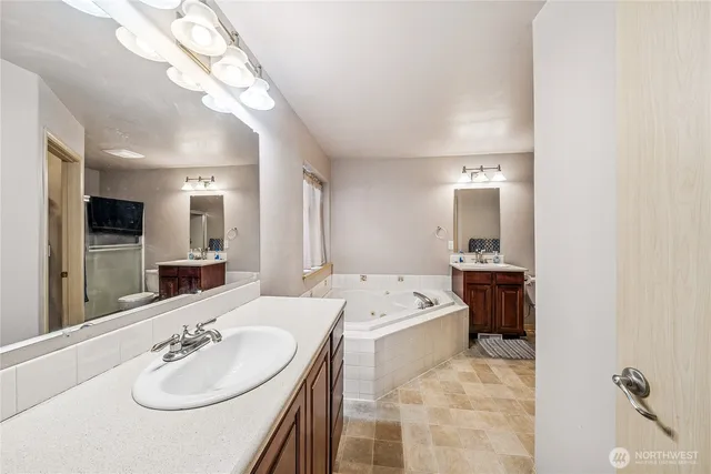 a en suite bathroom with a double vanity sink a mirror and bathtub
