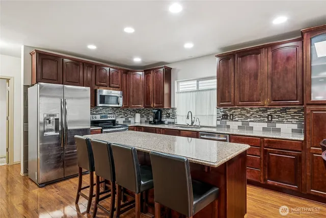 a kitchen with stainless steel appliances granite countertop a table chairs sink refrigerator and microwave