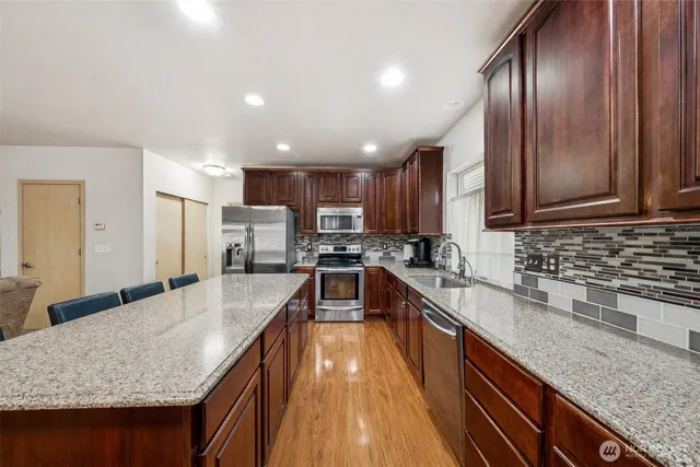 a kitchen with stainless steel appliances granite countertop sink stove refrigerator and cabinets