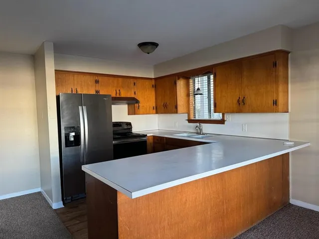 a kitchen with stainless steel appliances granite countertop a refrigerator a sink and a stove