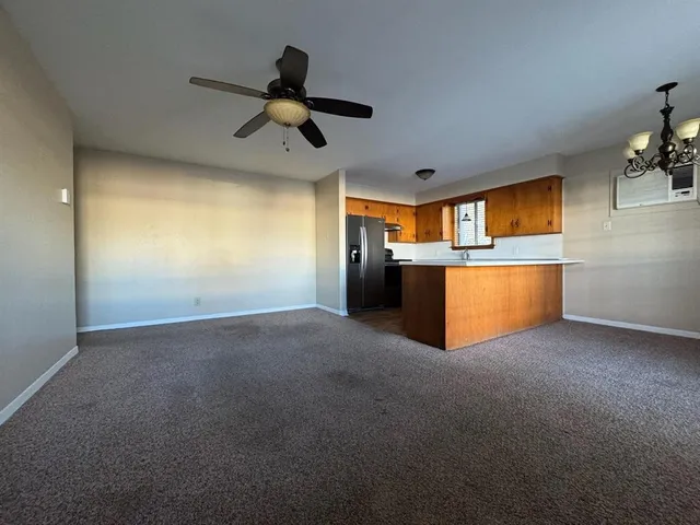 a view of a livingroom with a ceiling fan and kitchen