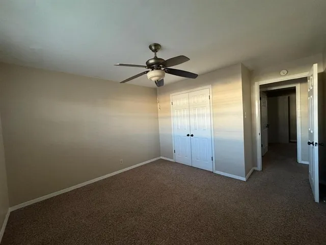 an empty room with a ceiling fan and a window