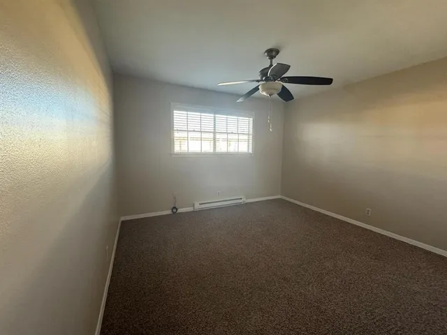 an empty room with a window and a fan