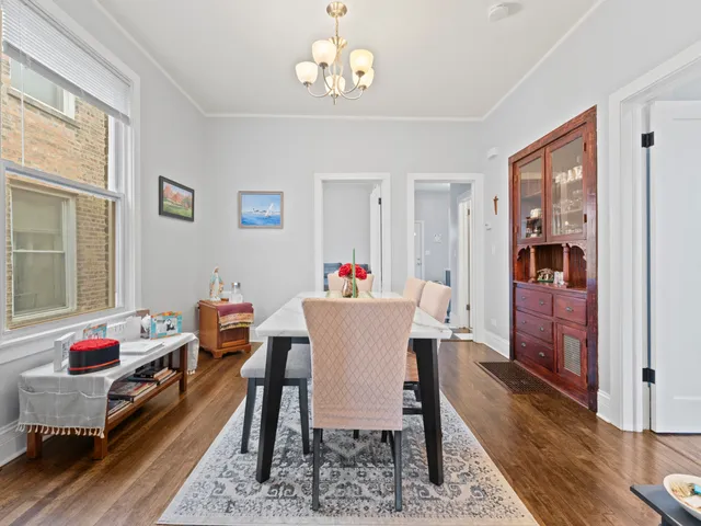 a dining room with wooden floor a chandelier a wooden table and chairs