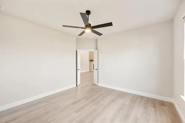 an empty room with wooden floor ceiling fan and window