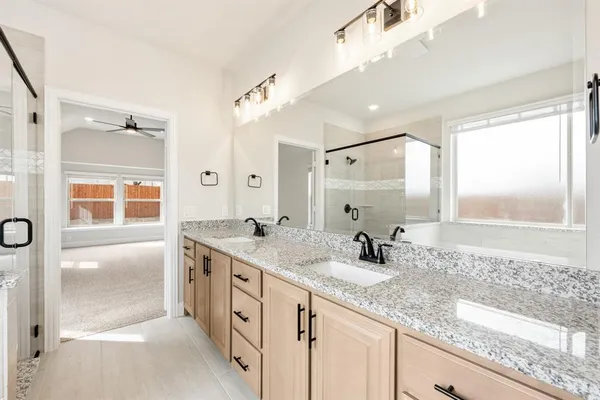 a bathroom with a granite countertop double vanity sink a mirror and shower