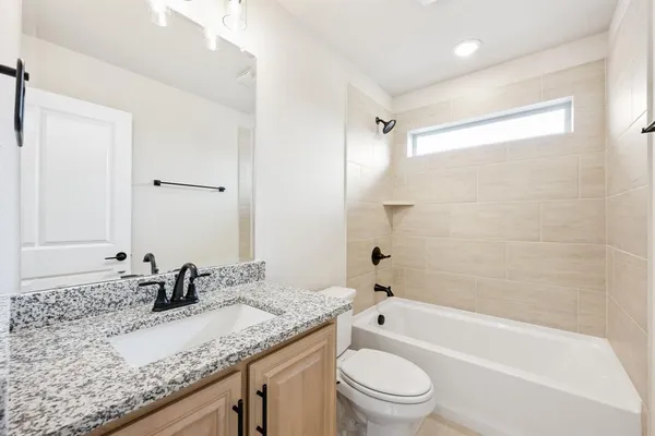 a bathroom with a granite countertop sink a toilet and bathtub