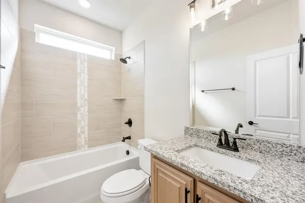 a bathroom with a granite countertop bathtub shower sink vanity mirror and toilet