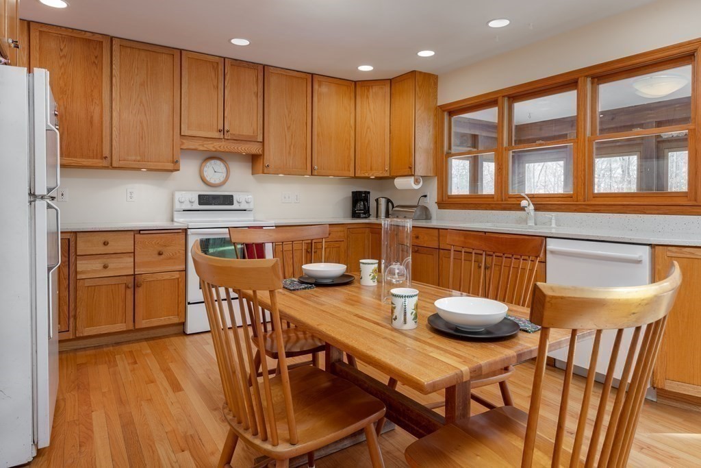 82 Nashoba Road Littleton, MA 01460 - Photo 6 of 39 a kitchen with stainless steel appliances granite countertop a stove a refrigerator a kitchen island a table and chairs with wooden floor