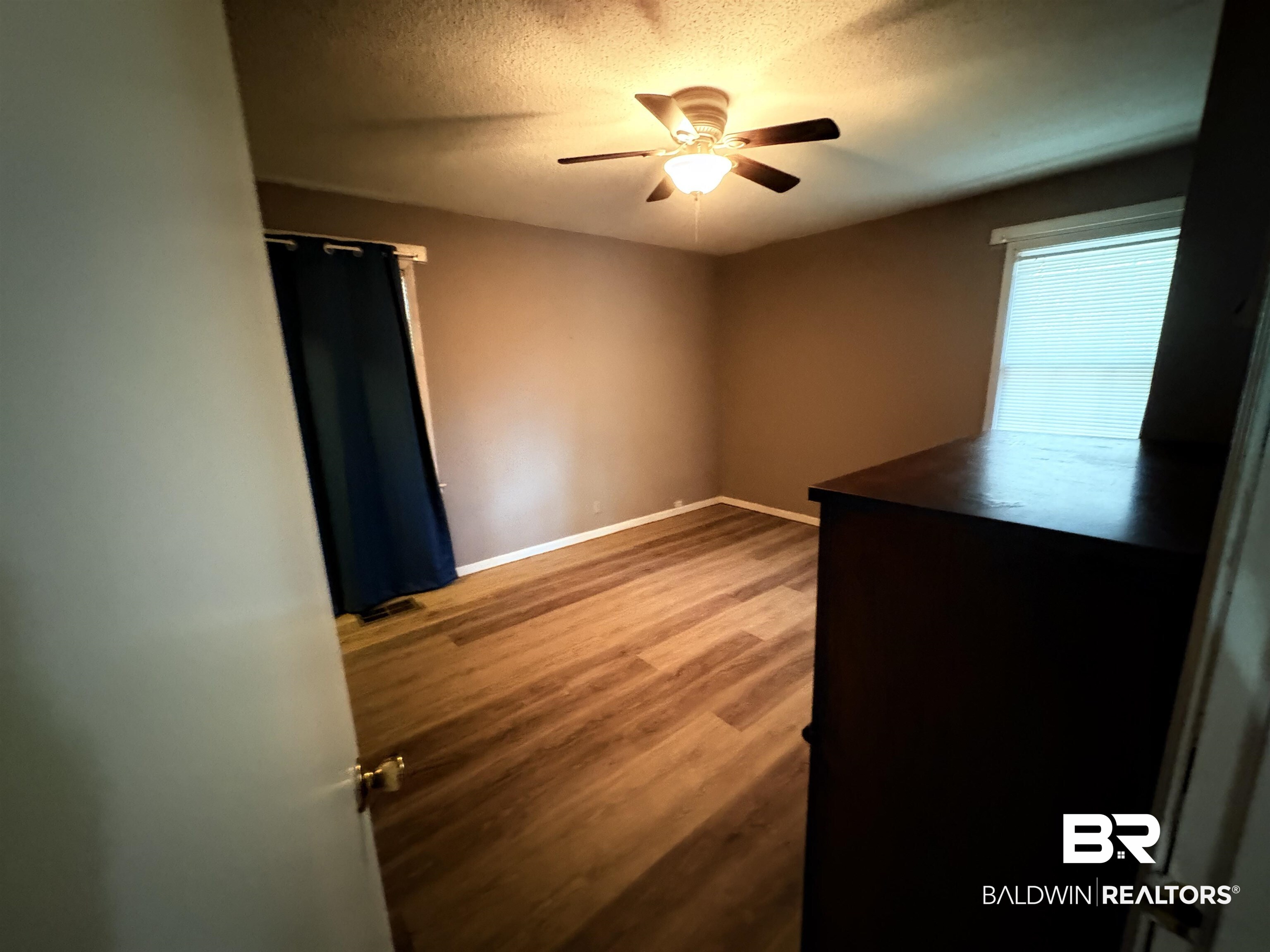8065 Middle Ring Road Mobile, AL 36619 - Photo 10 of 21 Unfurnished bedroom with a textured ceiling, a ceiling fan, baseboards, and wood finished floors