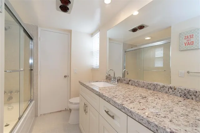 a bathroom with a granite countertop sink a toilet and shower